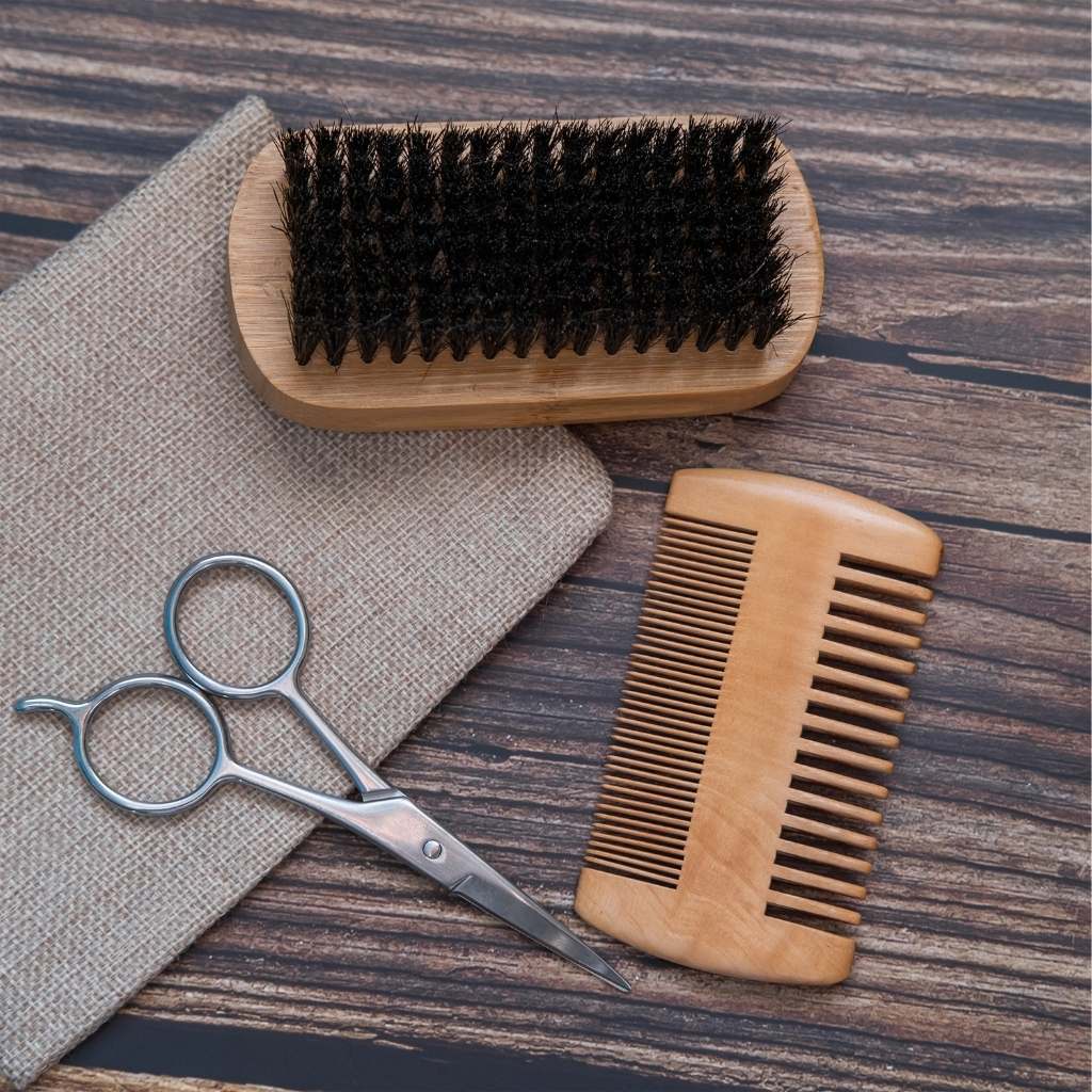 Beard Combs with fine and wide wooden teeth beside a black-bristled brush, silver scissors and beige fabric.