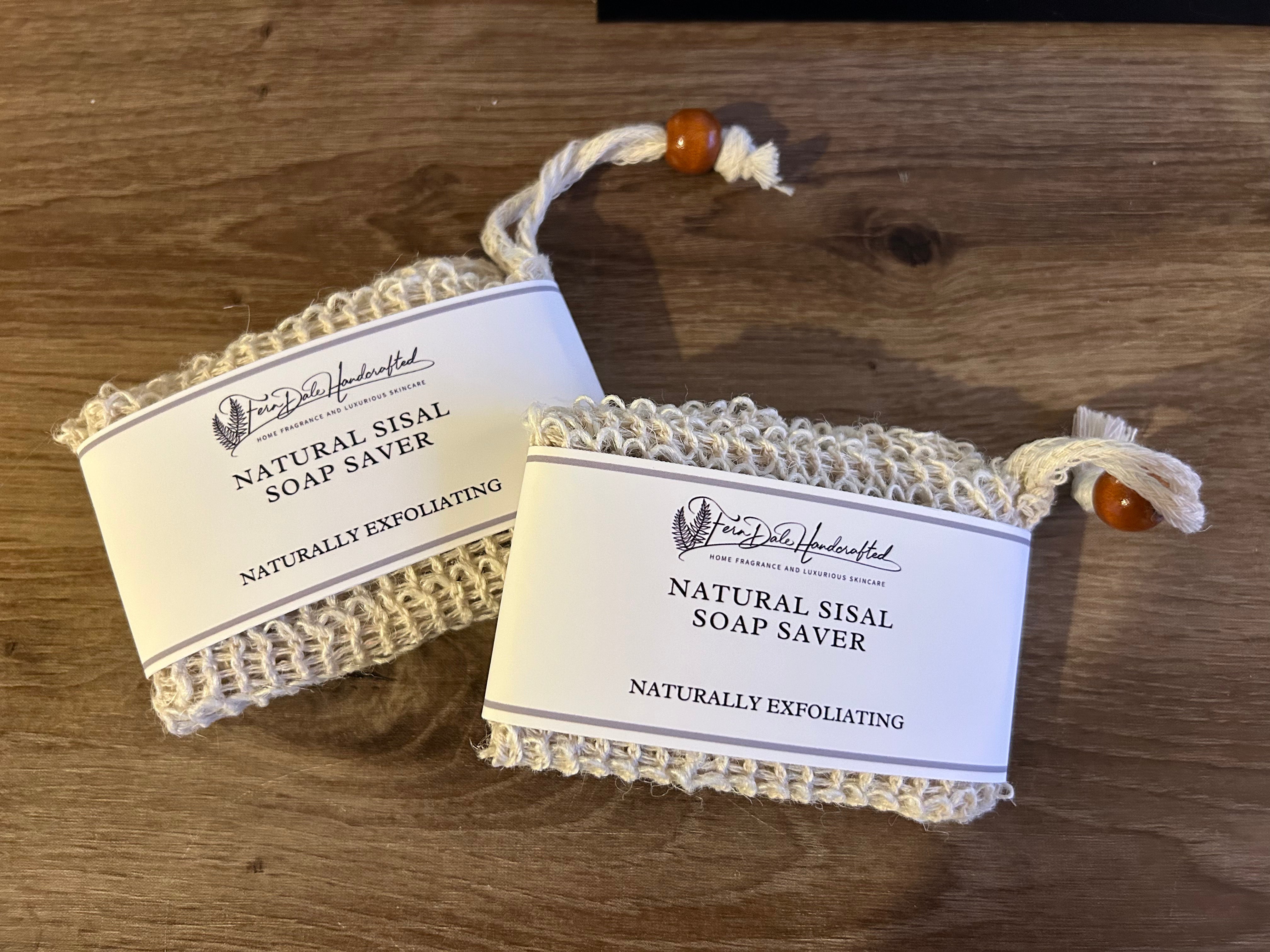 Two Natural Sisal Soap Saver pouches with white labels and beaded drawstrings on a wooden surface.